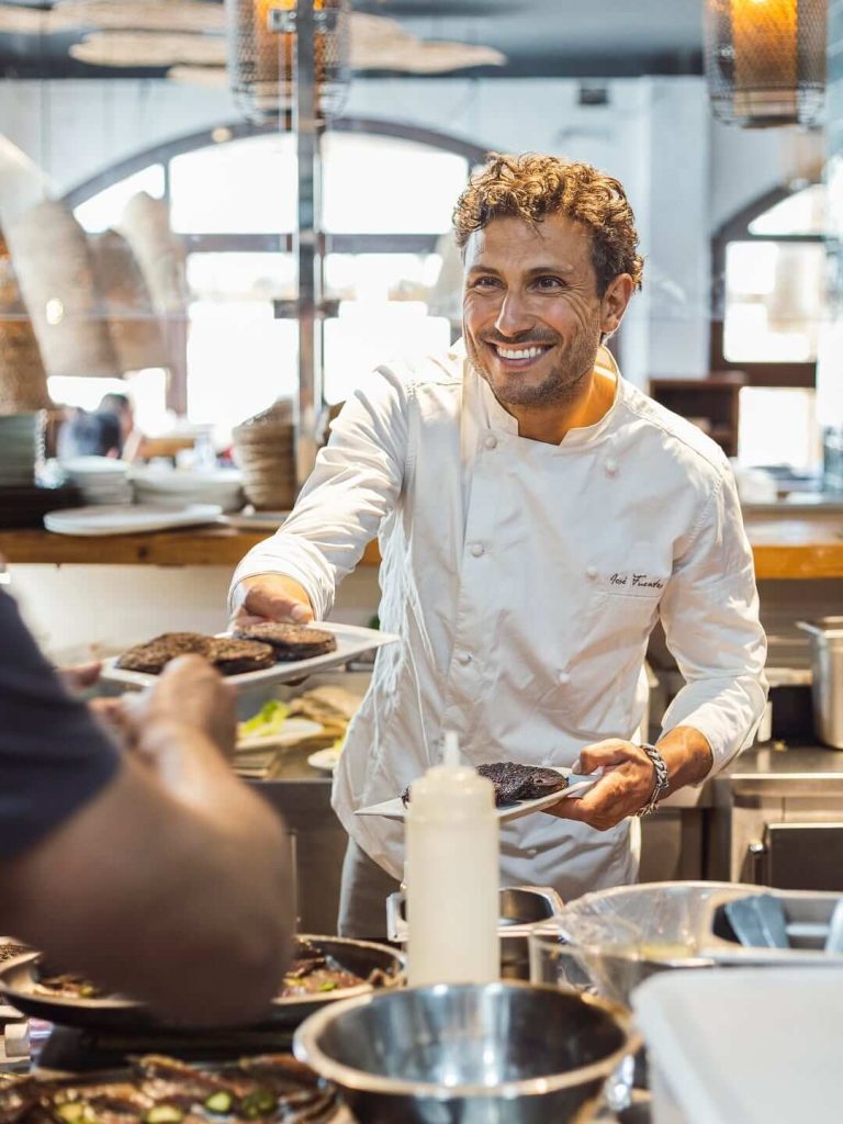 Home 3 El chef José Fuentes entregando platos en cocina abierta de Casa Candela, restaurante en Zahara de los Atunes